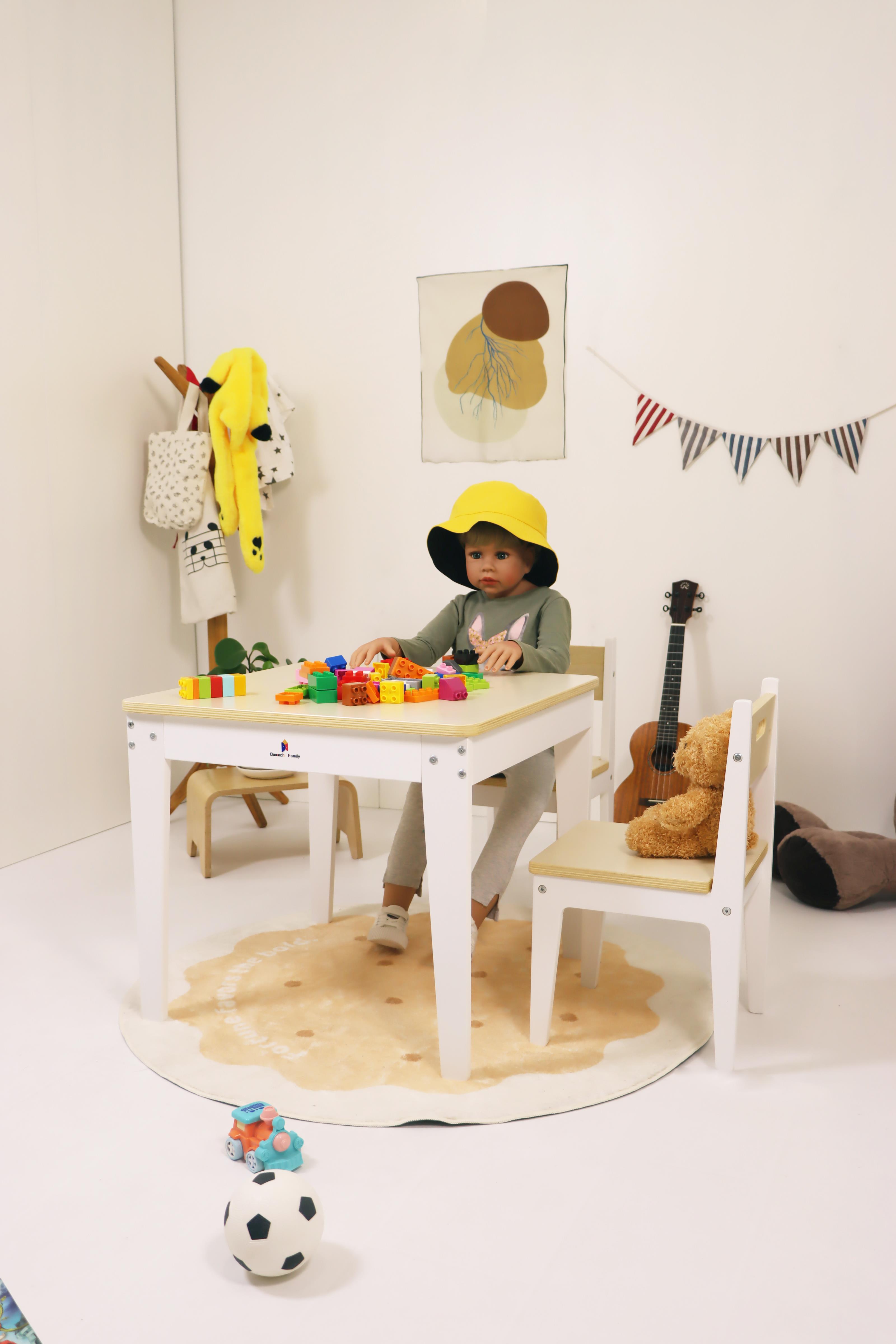 Toddler sitting on a wooden chair playing with toys at a children's table