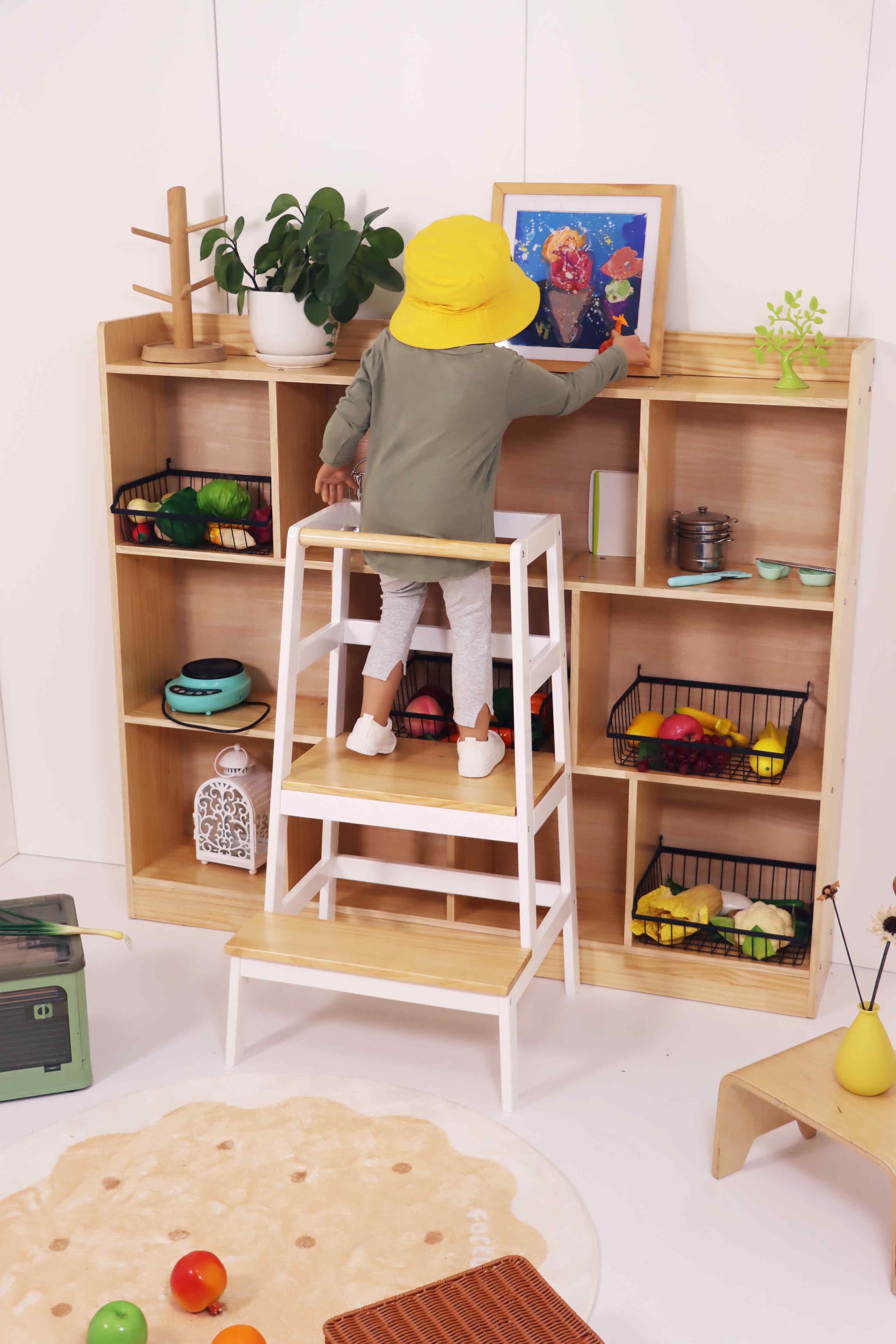 Toddler standing safely on wide step stool to reach high counter.