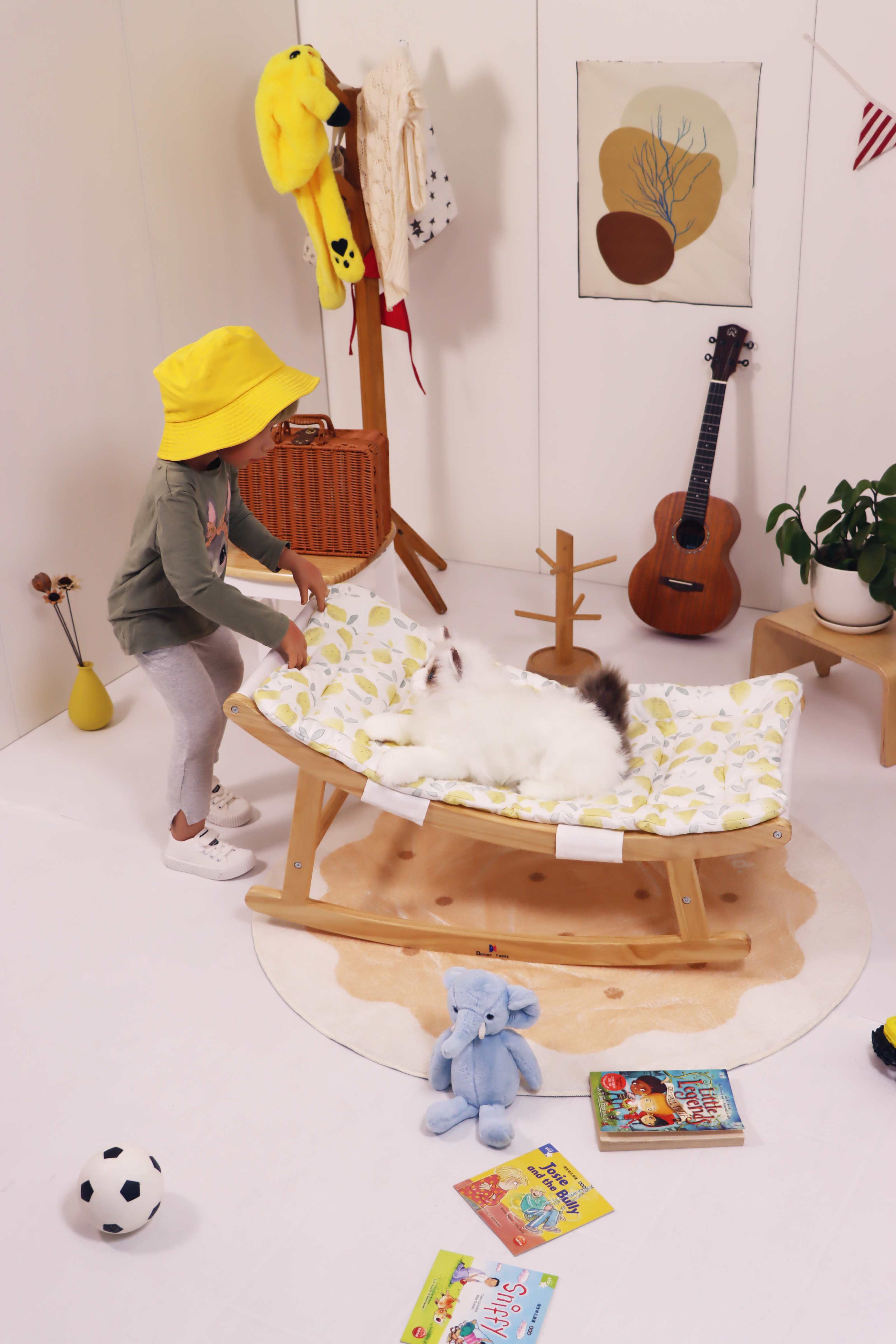 Cat lying on the Damoch Family baby rocker, toddler rocking the chair to play with the cat